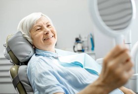 Older woman looking at her smile in dentist’s chair