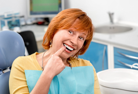 Woman in dental chair pointing to tooth