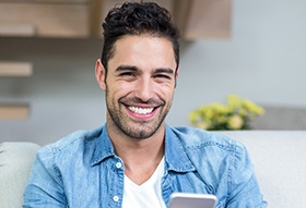 Man smiling while holding phone