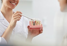dentist pointing to dental implant model