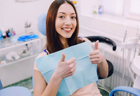 Smiling woman in a dental chair giving thumbs up