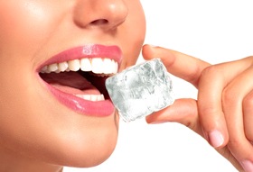 Woman with dental implants in Longview, TX chewing on block of ice