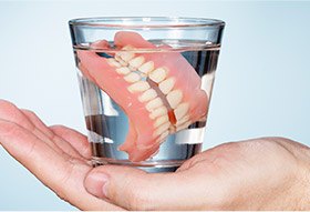 dentures in a glass cup filled with water
