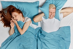 Red-haired woman snoring in bed, man covering ears