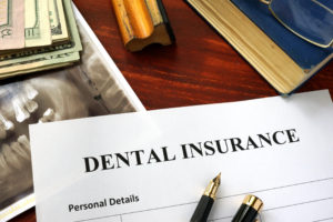 Dental insurance paperwork and X-ray on brown wooden desk 