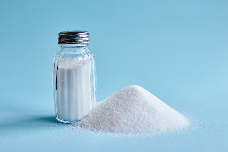 A shaker full of salt, placed artfully next to a pile of even more salt